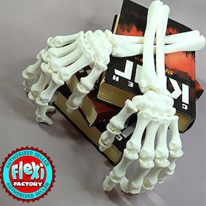 May include: A white articulated skeleton hand rests on a stack of books with red and black covers. The books have gold-coloured page edges. The image includes a Flexi Factory authorised seller logo.