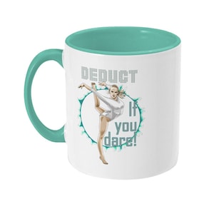May include: White ceramic mug with a teal interior and handle. The mug features a graphic of a gymnast in a white leotard, with the text "Deduct if you dare!" in a stylized font. The design is set against a teal and white background.