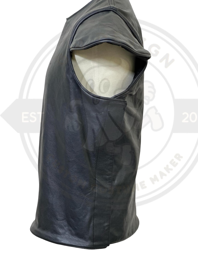 May include: A black leather vest with a unique design. The vest has a rounded shoulder cut and a smooth, matte finish. The garment is displayed on a mannequin, showcasing its shape and texture. The vest appears to be a sleeveless top.