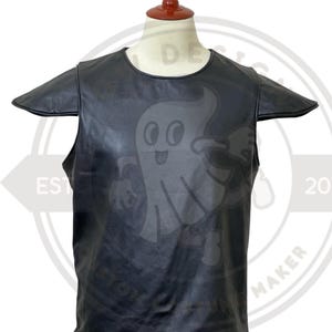May include: Black leather vest with a cartoon ghost graphic. The vest has short sleeves and a round neckline. The ghost graphic is centered on the front of the vest. The vest is displayed on a mannequin.