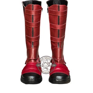 Peut inclure: Une paire de bottes rouges hautes avec des d&eacute;tails noirs. Les bottes montent jusqu'aux genoux et comportent des sangles et des fermetures &eacute;clair. Les semelles et les bouts sont noirs. Ces bottes font probablement partie d'un costume.