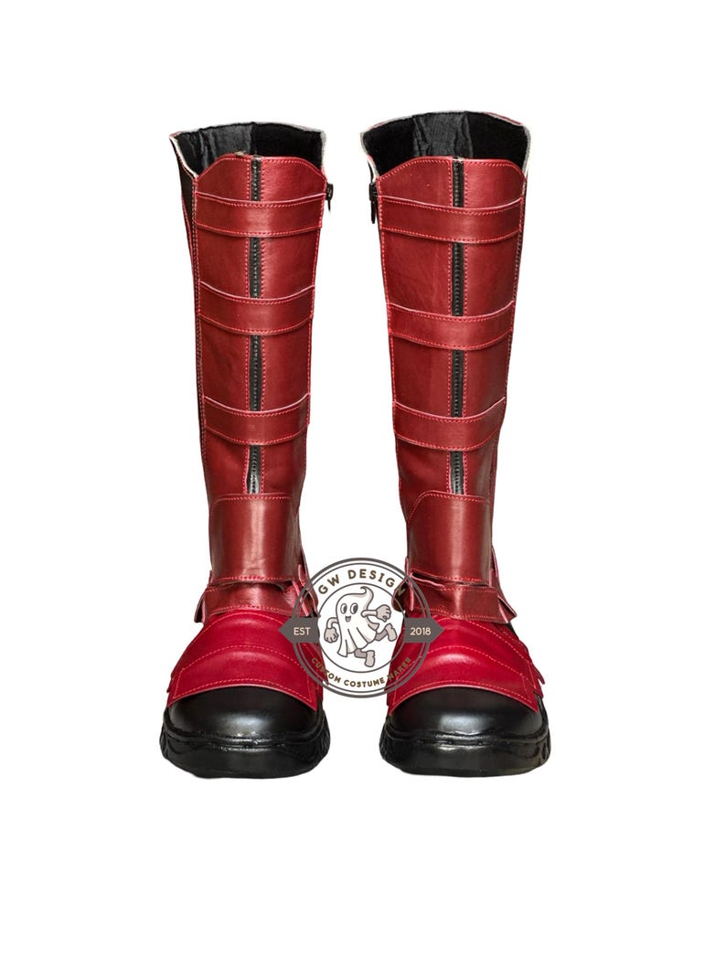 Peut inclure: Une paire de bottes rouges hautes avec des d&eacute;tails noirs. Les bottes montent jusqu'aux genoux et comportent des sangles et des fermetures &eacute;clair. Les semelles et les bouts sont noirs. Ces bottes font probablement partie d'un costume.