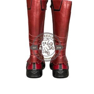 Peut inclure: Une paire de bottes rouges hautes avec des d&eacute;tails noirs. Les bottes montent jusqu'au genou et ont une fermeture &eacute;clair lat&eacute;rale. Les semelles sont noires. Les bottes semblent &ecirc;tre en cuir ou dans une mati&egrave;re similaire. Elles font partie d'un costume.