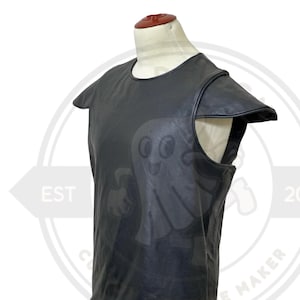 May include: Black leather vest with shoulder accents, displayed on a mannequin. The vest has a round neckline and a sleeveless design. The leather appears to be smooth and has a slight sheen. The vest is likely part of a costume or cosplay ensemble.