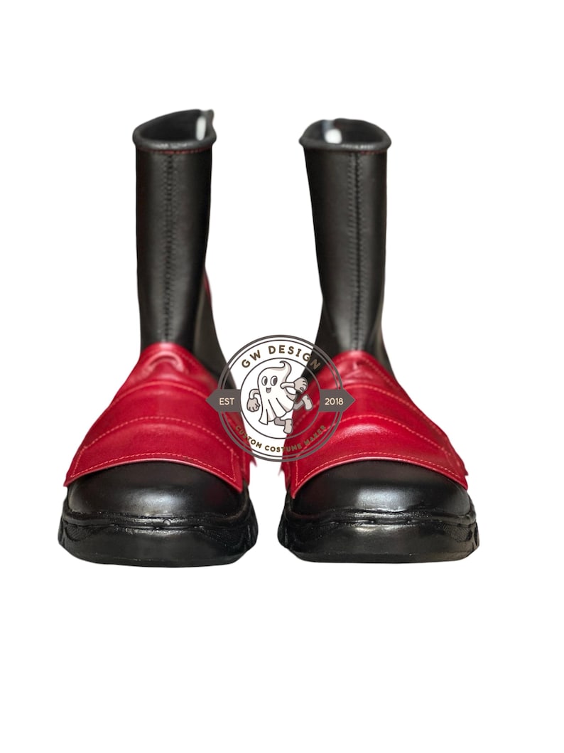 Peut inclure: Paire de bottes noires avec des d&eacute;tails rouges. Les bottes ont une tige haute et une sangle rouge sur le dessus du pied. Les bottes sont en mati&egrave;re lisse. Les bottes sont neuves et pr&eacute;sent&eacute;es sur fond blanc.