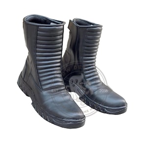 May include: A pair of black leather boots with a mid-calf height. The boots have a ridged design on the upper shaft and a rugged sole. The boots are new and unworn.