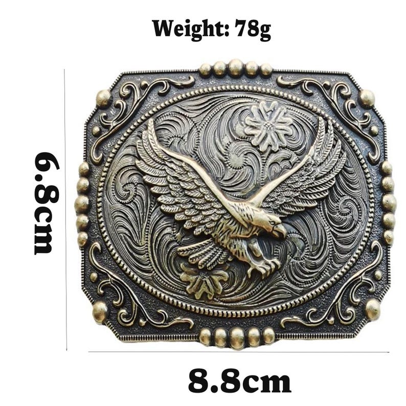 May include: A rectangular, antique-style belt buckle with an eagle design. The buckle is 3.5 inches wide and 2.7 inches tall, with a weight of 2.7 ounces. The eagle is centered, with outstretched wings, and surrounded by ornate scrollwork.