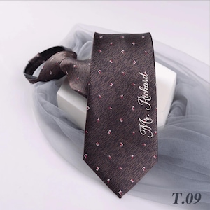 May include: A brown tie with a repeating pattern of small red and white squares. The words "Mr. Richard" are written in cursive on the tie. The tag "T.09" is in the bottom right corner.
