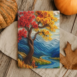 May include: An art print depicting a tree with red and yellow leaves, set against a blue river and mountain landscape. The artwork is displayed on a neutral cloth, with pumpkins and a leaf nearby.