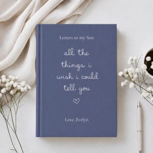 Może przedstawiać: Niebieski dziennik w twardej oprawie z białym napisem Letters to my Son, all the things i wish i could tell you oraz Love, Evelyn, z małą białą ikoną serca wyśrodkowaną pod tekstem na przedniej okładce książki.