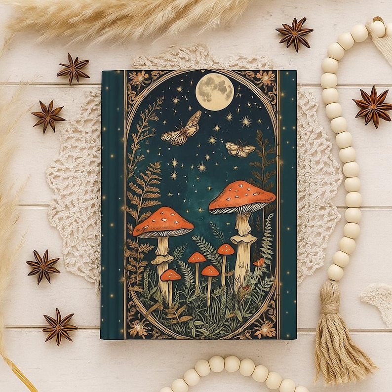 May include: A teal journal with a whimsical illustration of mushrooms under a full moon, butterflies, and stars. The cover features an ornate gold frame and botanical elements. The journal is a fantasy-themed notebook.