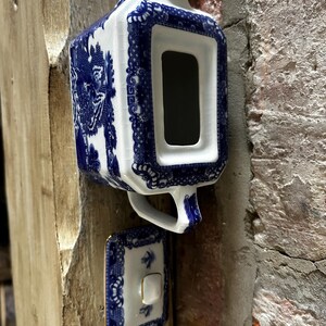 Peut inclure: Une th&eacute;i&egrave;re rectangulaire en c&eacute;ramique orn&eacute;e d'un motif bleu et blanc avec une finition craquel&eacute;e. La th&eacute;i&egrave;re comprend une anse, un bec verseur et un couvercle assorti dot&eacute; d'un petit bouton. Le d&eacute;cor pr&eacute;sente des bordures florales bleues.