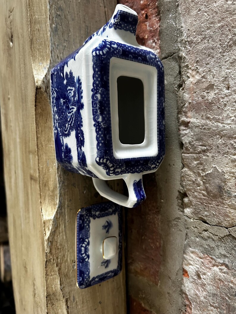 Peut inclure: Une th&eacute;i&egrave;re rectangulaire en c&eacute;ramique orn&eacute;e d'un motif bleu et blanc avec une finition craquel&eacute;e. La th&eacute;i&egrave;re comprend une anse, un bec verseur et un couvercle assorti dot&eacute; d'un petit bouton. Le d&eacute;cor pr&eacute;sente des bordures florales bleues.