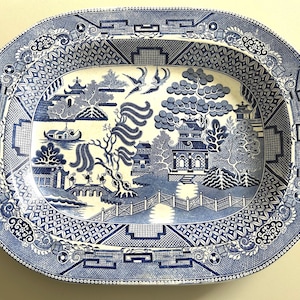 Puede incluir: Una taza de cerámica blanca con un asa negra y el texto "But First, Coffee" en negrita negra. La taza está sobre una superficie de madera. La taza mide 10 cm de alto.