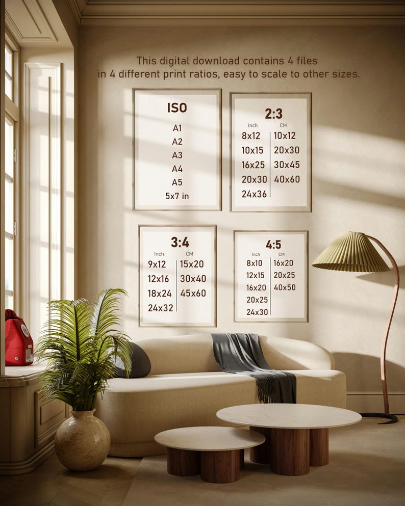 May include: Interior design image featuring a beige sofa, two round coffee tables, and framed art prints. The prints display size ratios in inches and centimeters. A floor lamp with a pleated shade and a potted plant add to the room's decor.