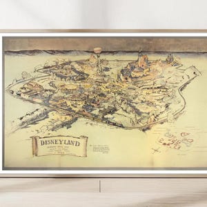 Könnte beinhalten: Eine gerahmte, im Vintage-Stil gehaltene Karte von Disneyland mit einer sepiafarbenen Illustration des Parkplans. Der Druck enthält ein Banner mit dem Text DISNEYLAND, eine Windrose und detaillierte Skizzen verschiedener Attraktionen.