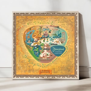 May include: A square framed map of Disneyland in Anaheim, California, featuring a golden-yellow background with intricate line drawings of park attractions. The central area displays a colorful park layout with labeled lands and a train track.