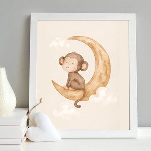 May include: Watercolor illustration of a brown monkey sitting on a crescent moon, surrounded by fluffy clouds. The artwork is framed in a white border, creating a whimsical nursery or children's room decor.