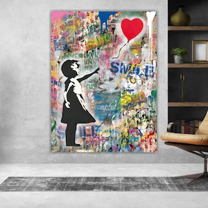 Puede incluir: Una gran obra de arte en lienzo que presenta una silueta negra de una niña que alcanza un globo rojo en forma de corazón. El fondo es una vibrante mezcla de salpicaduras de pintura estilo graffiti en varios colores, con la palabra "SMILE" visible.