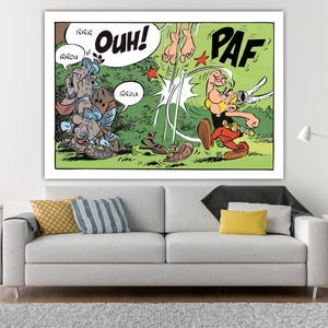 Può includere: Stampa di fumetto incorniciata con una scena con personaggi dei cartoni animati. Un personaggio colpisce un altro, con effetti sonori come "OUH!" e "PAF." L'opera d'arte ha uno sfondo verde e bianco, con personaggi in rosso, giallo e blu.