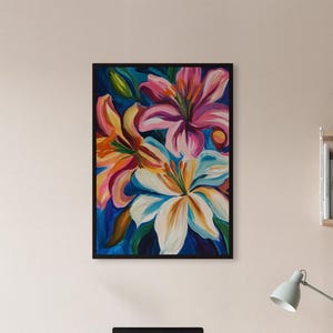 May include: A framed floral painting featuring vibrant lilies in shades of pink, orange, and white against a dark blue background. The artwork is displayed on a light wooden desk, adding a touch of color to the room.
