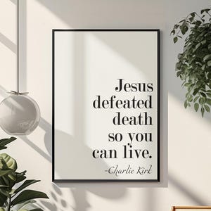 Może przedstawiać: Oprawiony wydruk z tekstem "Jesus defeated death so you can live. -Charlie Kirk" w czarnej ramie. Wydruk wisi na białej ścianie, z drewnianym krzesłem i roślinami w tle.