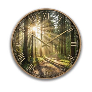 May include: Round wall clock with a forest scene. The clock face features a photograph of a sunlit forest path. The clock has gold-colored hands and Roman numerals. The clock is framed in a light brown wood.