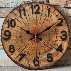 May include: A circular wooden clock with a natural wood grain. The clock face has black numerals and hands, with a red second hand. The clock is made from a tree trunk cross-section, displaying the wood's texture and natural markings.