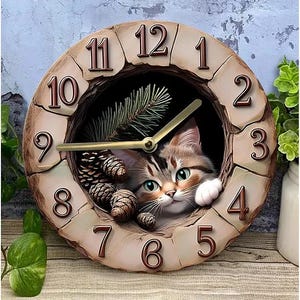 Op de afbeelding: Decoratieve wandklok met een kat in het midden. De klok heeft Romeinse cijfers en gouden wijzers, met een steenachtig effect. Er zijn ook dennenappels en groen te zien.