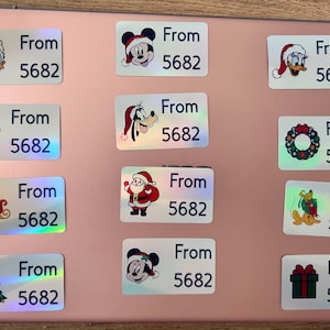 May include: A collection of rectangular labels with various holiday-themed illustrations, including Mickey Mouse, Donald Duck, Santa Claus, and a Christmas tree. Each label has the text "From 5682".