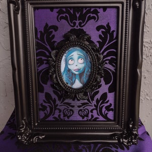 May include: A black picture frame with a purple velvet background and a black and white image of a character from the movie "The Nightmare Before Christmas".