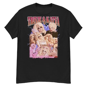 May include: Black t-shirt featuring a graphic of multiple images of Trixie & Katya, with the text "Trixie & Katya" in a vintage style font. Below the images is the text "Real Life Women".
