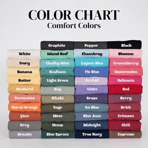 May include: A color chart for Comfort Colors featuring a grid of folded fabric swatches in various shades. The text at the top reads COLOR CHART Comfort Colors, followed by rows of labeled colors including White, Ivory, Banana, Butter, Mustard, Terracotta, Burnt Orange, Yam, Grey, Granite, Graphite, Pepper, Black, Island Reef, Chalky Mint, Seafoam, Light Green, Bay, Khaki, Sage, Moss, Hemp, Blue Spruce, Chambray, Lagoon Blue, Flo Blue, Orchid, Violet, Grape, Ice Blue, Blue Jean, Midnight, True Navy, Blossom, Crunchberry, Watermelon, Heliconia, Red, Berry, Brick, Crimson, Chili, and Espresso.