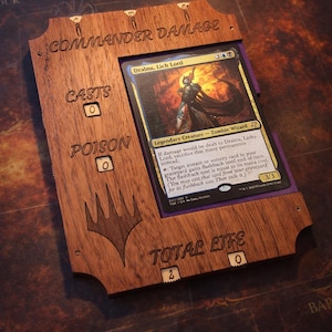 May include: Wooden Commander Damage and Life counter for a Magic: The Gathering card. The frame has etched text: "Commander Damage", "Casts", "Poison", and "Total Life". A card with a zombie wizard is displayed.