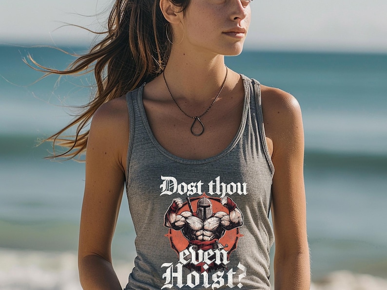 K&ouml;nnte beinhalten: Graues Tanktop mit dem Text "Dost thou even Hoist?" und einer Grafik einer muskul&ouml;sen Figur mit Helm. Das Tanktop ist &auml;rmellos und aus weichem Material. Der Hintergrund ist eine verschwommene Strandszene.