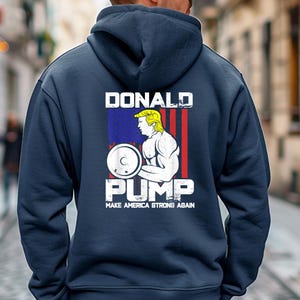 Peut inclure: Sweat à capuche bleu marine avec un motif graphique au dos. Le motif présente une illustration de dessin animé d'un homme soulevant des poids, avec le texte "DONALD PUMP" au-dessus et "MAKE AMERICA STRONG AGAIN" en dessous.