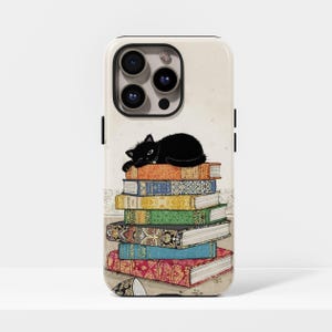 Può includere: Custodia per telefono con un gatto nero addormentato su una pila di libri colorati. I libri hanno copertine arancioni, blu, verdi e gialle. Lo sfondo è color crema e il bordo nero.