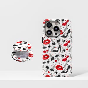 May include: A white phone case and a pop socket with a repeating pattern of red lips, black high heels, sunglasses, and stars. The phone case has a black camera lens and buttons.