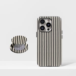 May include: A black and cream striped phone case and matching phone grip. The phone case has a black border around the camera lenses. The phone grip is round and has a collapsible design.
