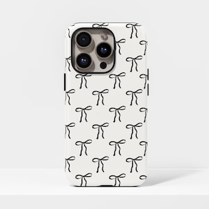 May include: A white phone case with a repeating pattern of black bow illustrations. The case has a glossy finish and features a camera cutout. The bows are evenly spaced across the surface, creating a simple yet elegant design.