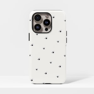 Peut inclure: Coque de téléphone blanche ornée de petites empreintes de pattes noires. Le boîtier est doté d'un cadre d'objectif de caméra noir et de boutons latéraux noirs. Conçu pour un smartphone.
