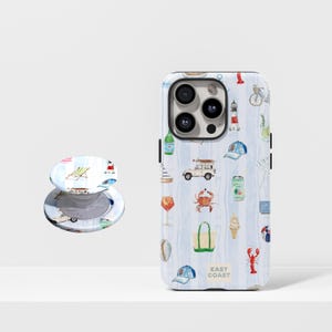 Op de afbeelding: Een telefoonhoesje en telefoonhouder met een kustthema. De hoes heeft een blauw-wit gestreepte achtergrond met illustraties van strandartikelen zoals een vuurtoren en een krab. De telefoonhouder heeft een strandstoelontwerp.