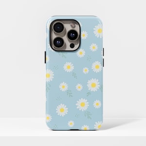 May include: A light blue phone case with a pattern of white daisies with yellow centres and green leaves. The case has a glossy finish and a black camera module.