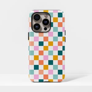 Puede incluir: Una funda de teléfono blanca con un patrón de tablero de ajedrez colorido. Los cuadrados son en tonos de rosa, naranja, turquesa, amarillo y verde oscuro. La funda tiene un módulo de cámara negro y botones laterales negros.