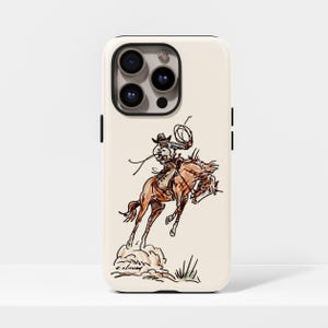 Pode incluir: Capa de telefone creme com um esboço de um cowboy montando um cavalo selvagem. O cowboy usa um chapéu e segura um laço. O cavalo é marrom, e a obra de arte inclui poeira e grama.