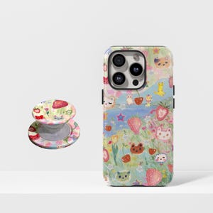 May include: A phone case and a phone grip featuring a whimsical design with strawberries, cats, and other cute illustrations. The case is a vibrant mix of colors, while the grip has a matching design.