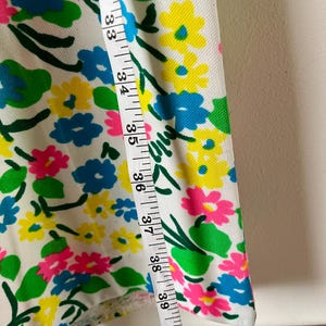 Puede incluir: Tela blanca con un vibrante estampado floral en rosa, amarillo y azul. Una cinta m&eacute;trica muestra medidas de 81 a 104 cm. El dise&ntilde;o se completa con hojas y tallos verdes.