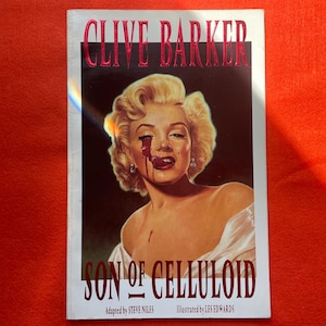 May include: A book cover featuring a woman with blonde hair and a red stain on her face. The title of the book is "Son of Celluloid" by Clive Barker. The book is adapted by Steve Niles and illustrated by Les Edwards.