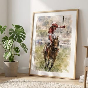 Peut inclure: Impression aquarelle encadrée d'une course de chevaux. Un jockey en rouge et blanc lève sa cravache sur un cheval brun. L'œuvre est encadrée dans un cadre en bois clair, sur fond neutre.