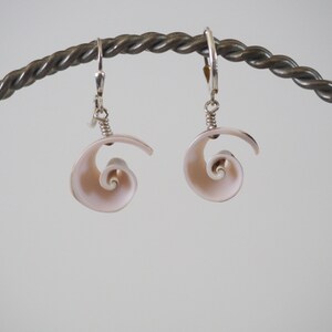 May include: A pair of silver earrings with a pink seashell spiral design.